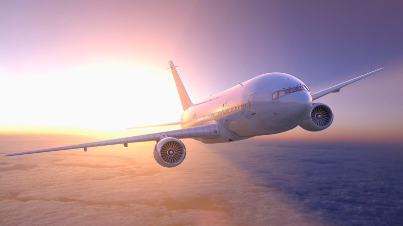 Airplane flying above clouds at sunset